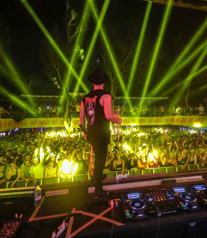 Timmy Trumpet with his trumpet on stage under green lasers, facing the Zrce Spring Break crowd