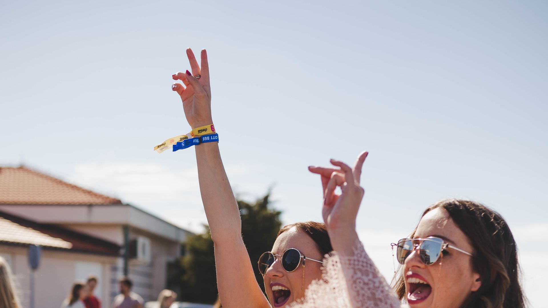 Two friends cheering with their festival wristbands at the Zrce Spring Break check-in