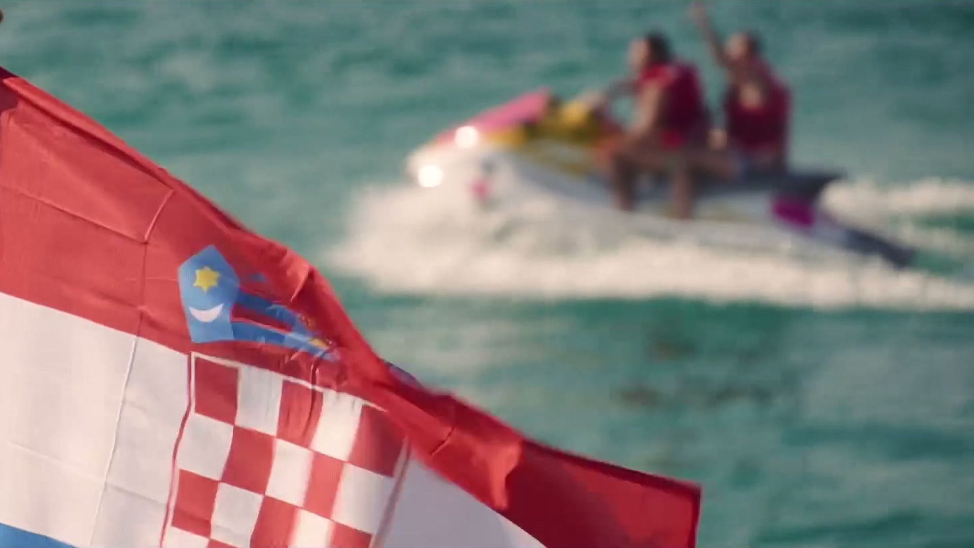 Croatian flag on a boat with a jet ski on the Adriatic behind it
