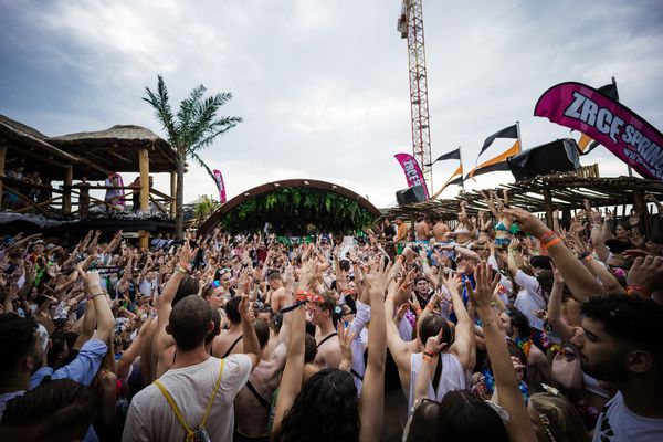 Daytime crowd with arms up at an open-air beach party