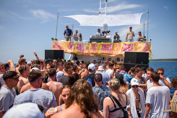Boat party crowd dancing in front of the DJ deck