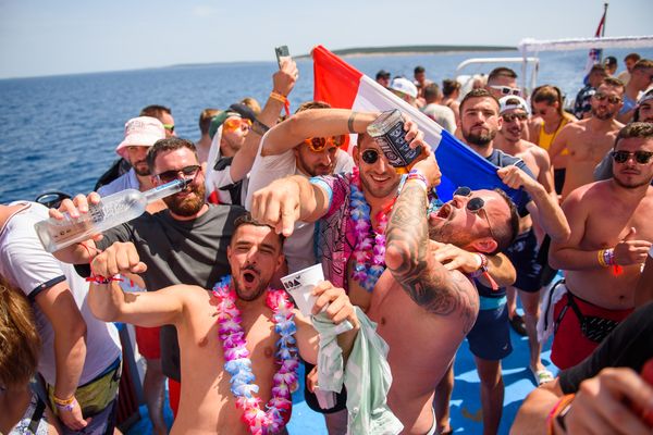 Boat party crowd cheering with flags and flower garlands