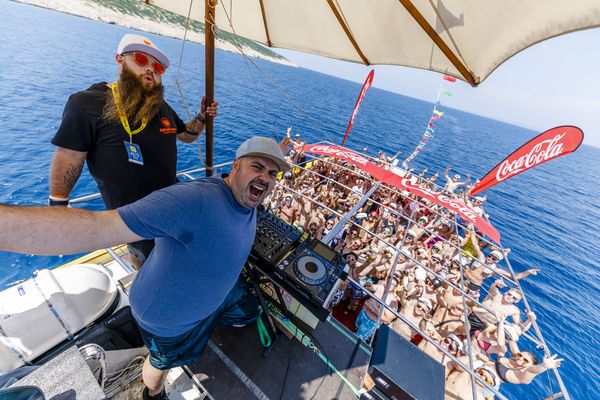 DJ on the party boat with the cheering crowd on deck behind him