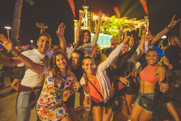 Friends with arms up at a night party by the stage