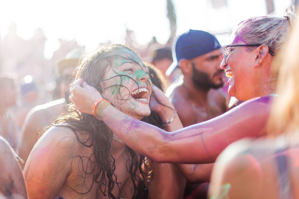 Friends laughing, covered in colour powder