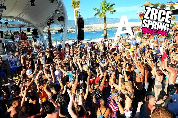 Huge pool party crowd with arms up by the sea