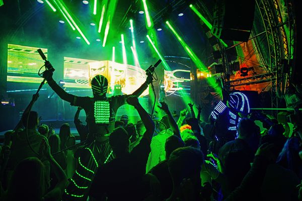 LED robots dancing in the crowd under green lasers